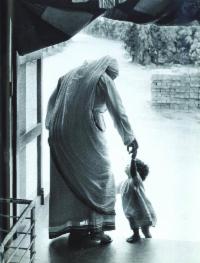 black and white photo of Mother Teresa holding the hand of a small child