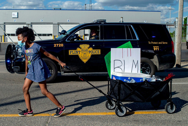 Black Lives Matter protester in Flint, MI, with a police SUV in the background