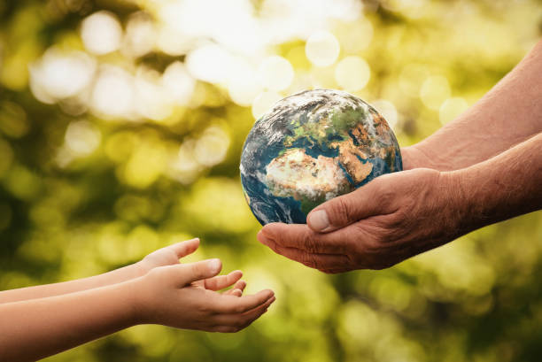 adult hands passing a model of the Earth to a young child