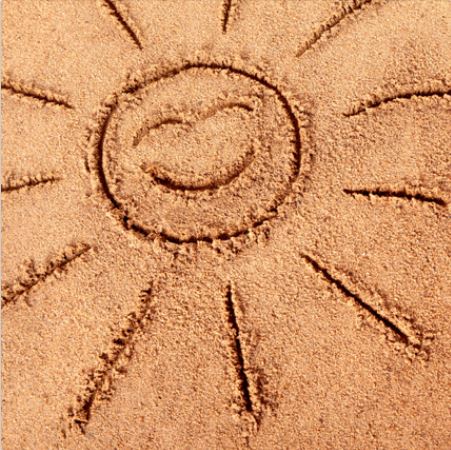 a drawing in the sand of a smiling sun